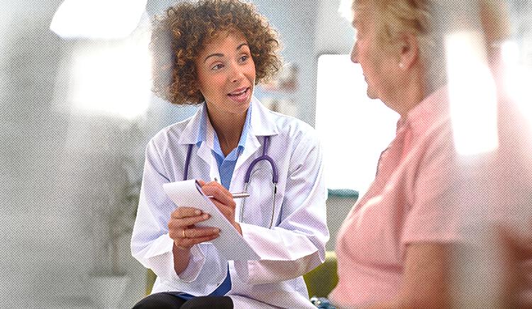 A doctor writes on a notepad while discussing the PureWick&trade; System with her patient
